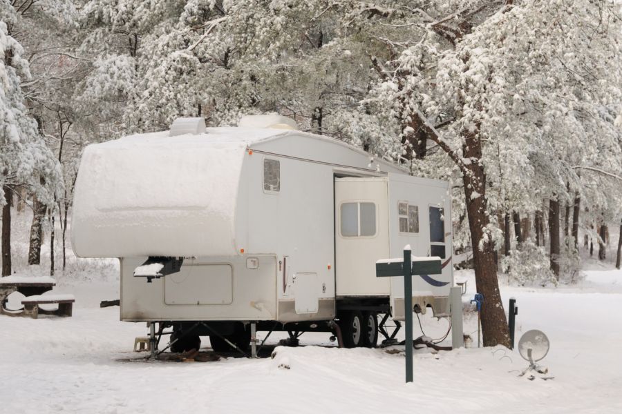 https://www.rvngo.com/onthego/wp-content/uploads/2023/03/Winter-RV-camping-RV-parked-at-campsite-during-winter-and-covered-in-snow.jpg